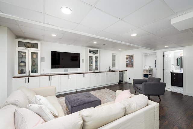 living area with beverage cooler, a drop ceiling, dark wood finished floors, and recessed lighting