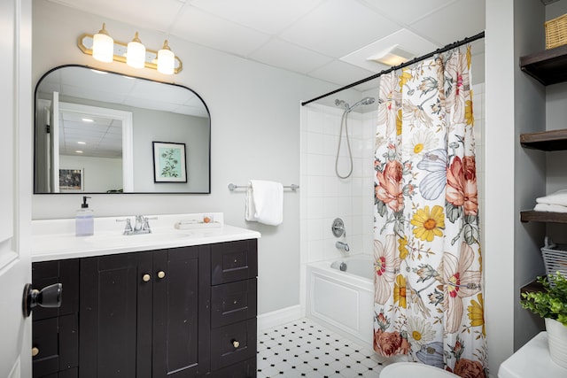 bathroom featuring toilet, a drop ceiling, shower / bath combo with shower curtain, and vanity