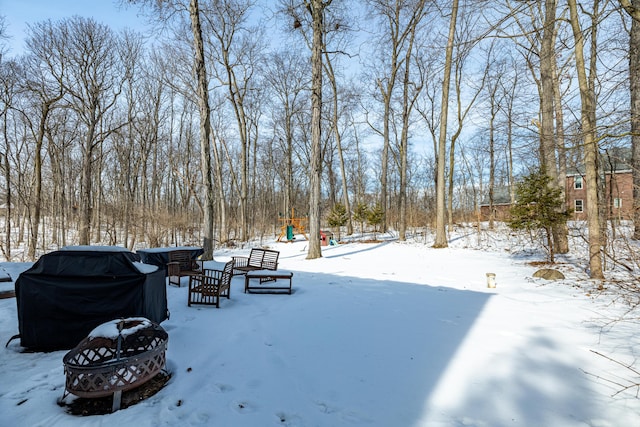 yard covered in snow with an outdoor fire pit and a playground