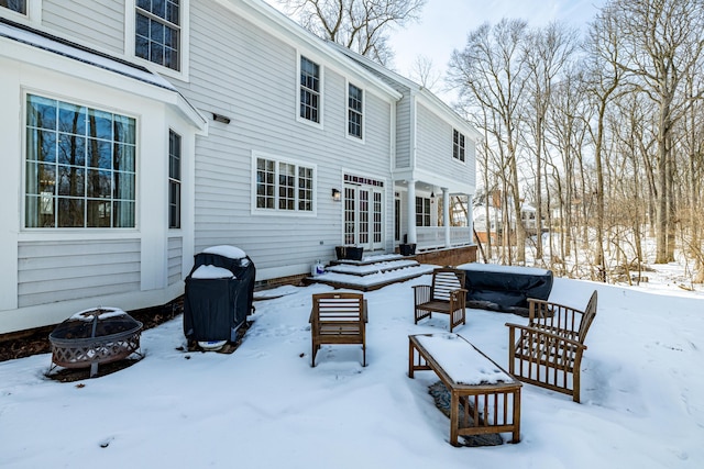 snow covered patio featuring a garage, a fire pit, and grilling area