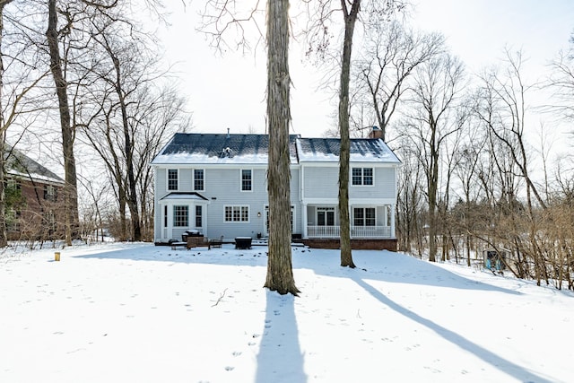 snow covered house with entry steps and a chimney