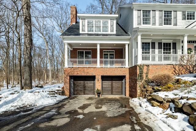 view of front facade with aphalt driveway, brick siding, a chimney, and a garage