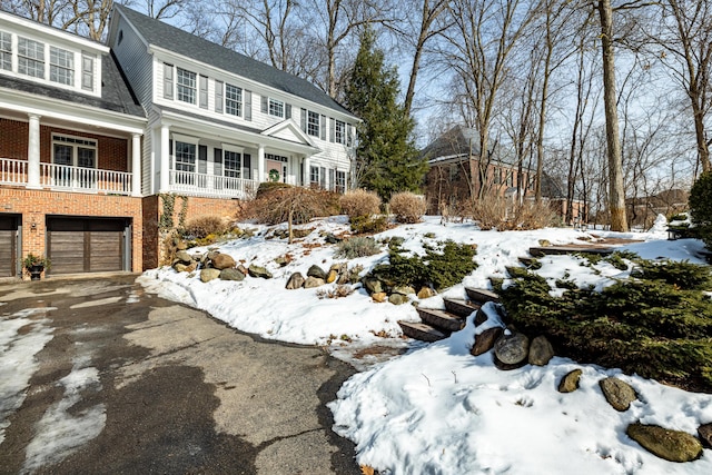 view of front facade with a garage, driveway, brick siding, and a shingled roof