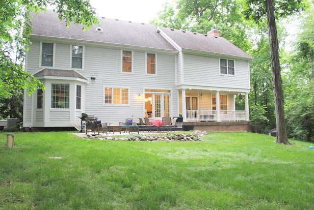 rear view of house with a yard, a shingled roof, a chimney, and an outdoor living space