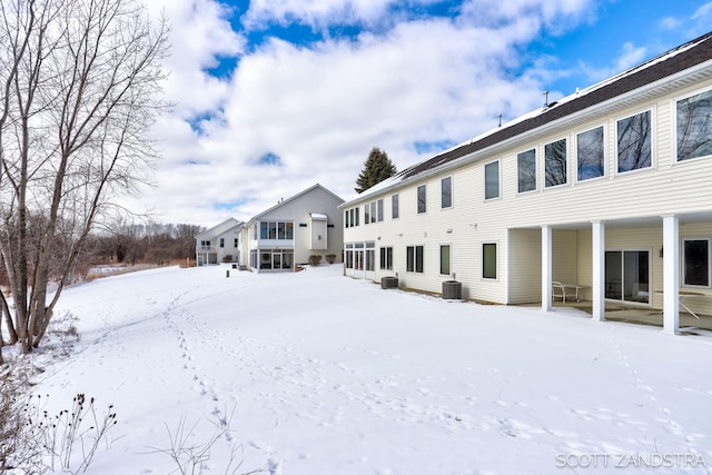 snow covered rear of property featuring cooling unit