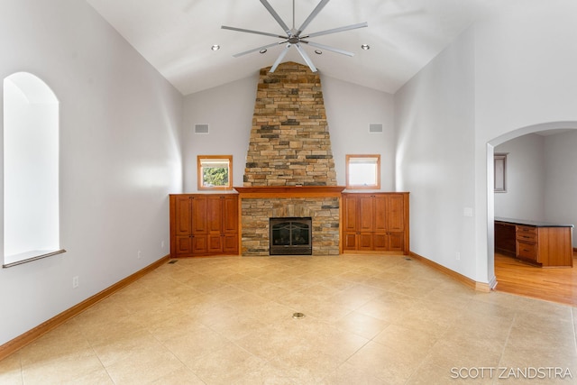 unfurnished living room featuring arched walkways, visible vents, a stone fireplace, high vaulted ceiling, and baseboards