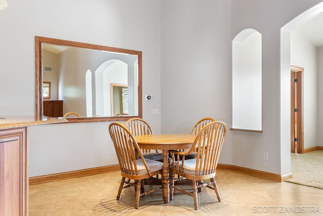 dining area featuring light tile patterned floors, baseboards, and arched walkways