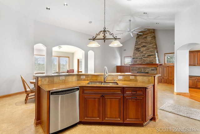 kitchen with an island with sink, open floor plan, decorative light fixtures, stainless steel dishwasher, and a sink