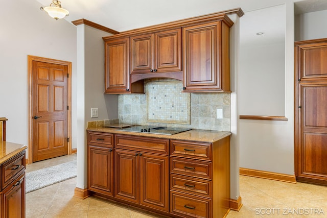 kitchen with light stone counters, brown cabinets, light tile patterned floors, tasteful backsplash, and baseboards