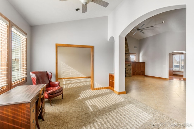 sitting room featuring a healthy amount of sunlight, ceiling fan, arched walkways, and baseboards