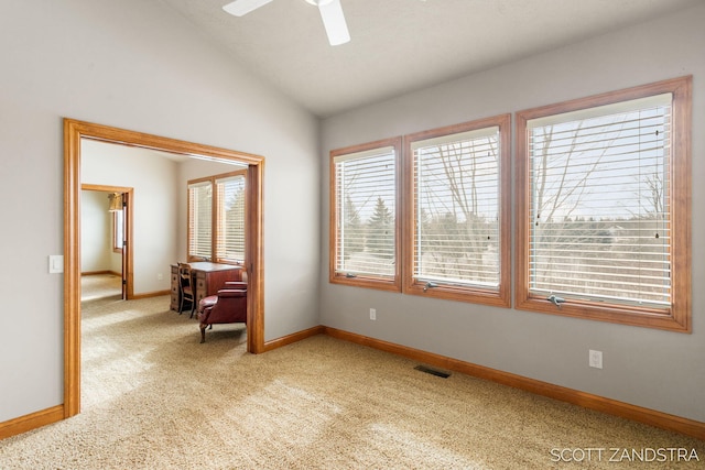 spare room featuring lofted ceiling, light colored carpet, a ceiling fan, baseboards, and visible vents