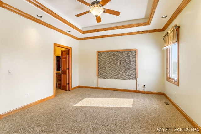 empty room featuring carpet floors, ornamental molding, a raised ceiling, and visible vents