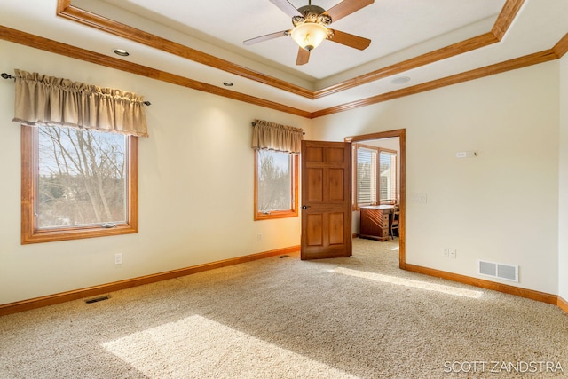 spare room featuring baseboards, a raised ceiling, visible vents, and crown molding