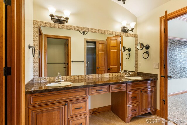 full bathroom featuring tile patterned floors, vaulted ceiling, a sink, and double vanity