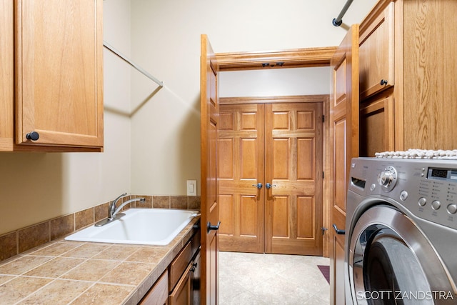 laundry area featuring cabinet space, a sink, and washer / dryer