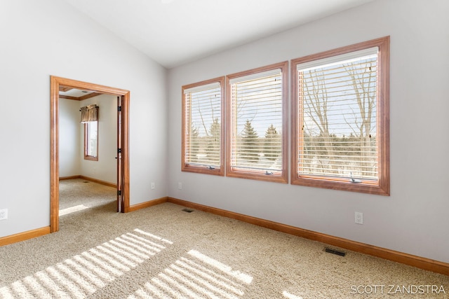 spare room featuring light carpet, baseboards, visible vents, and vaulted ceiling