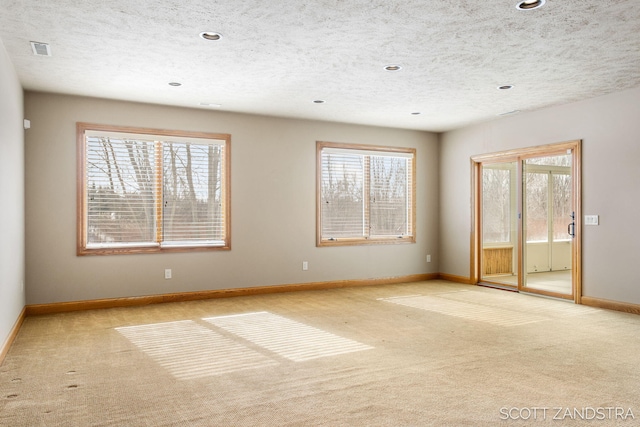 spare room with visible vents, a wealth of natural light, and light colored carpet