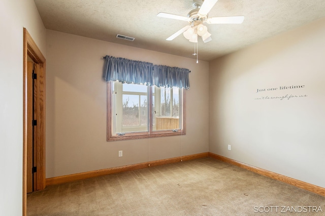 carpeted empty room with a ceiling fan, baseboards, visible vents, and a textured ceiling