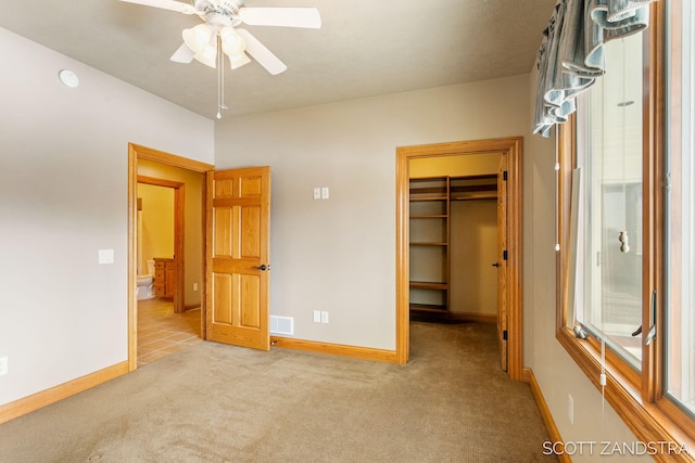 unfurnished bedroom with light carpet, baseboards, visible vents, and a walk in closet