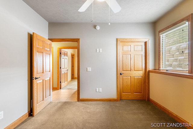 unfurnished bedroom featuring baseboards, a textured ceiling, and light colored carpet