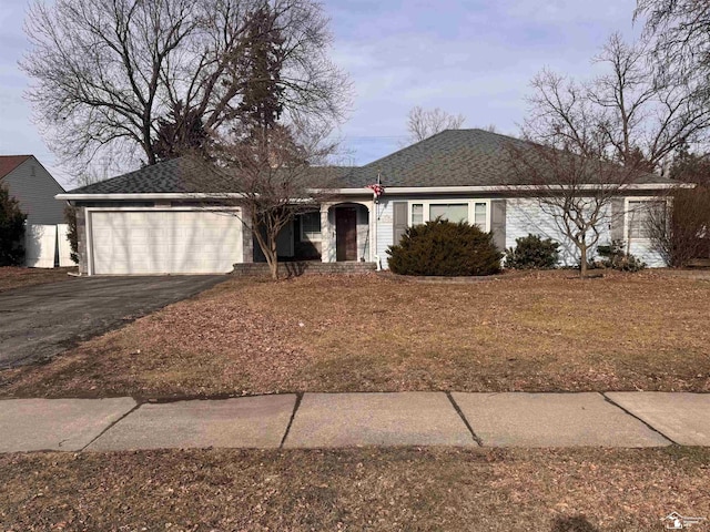 ranch-style home featuring a garage, a shingled roof, and aphalt driveway