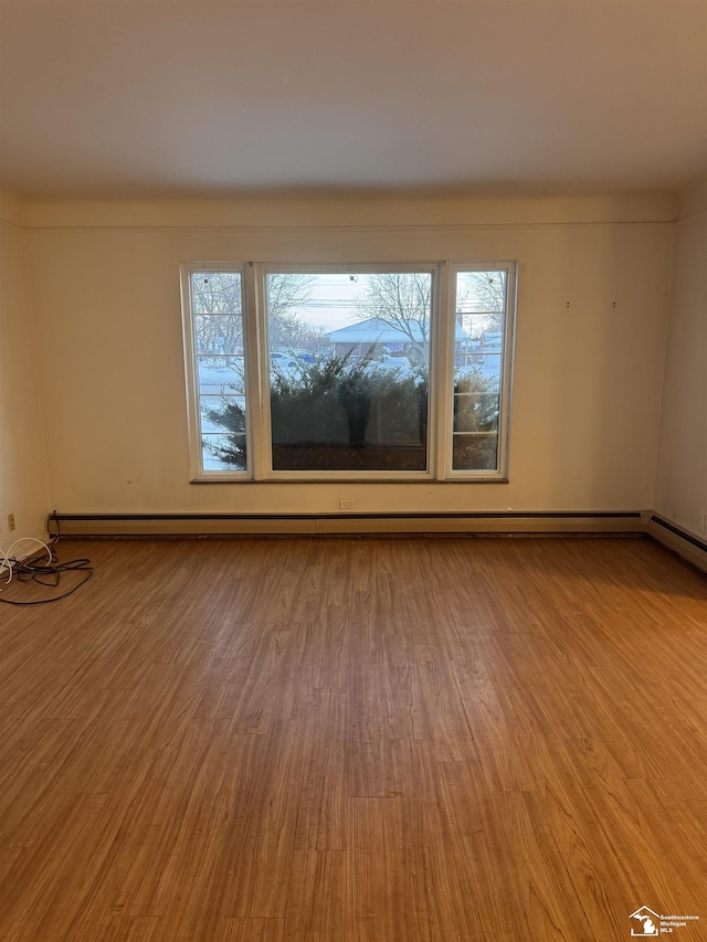 empty room with light wood finished floors and a baseboard heating unit