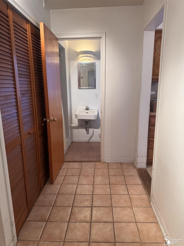 hallway with light tile patterned floors and a sink