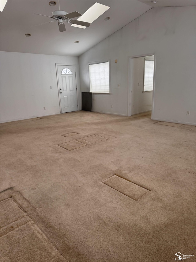 interior space featuring ceiling fan, lofted ceiling with skylight, and light colored carpet