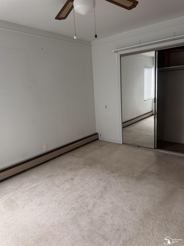 unfurnished bedroom featuring a baseboard heating unit, a closet, and a ceiling fan