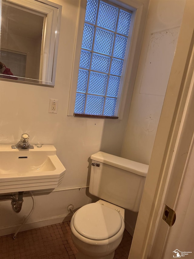 bathroom featuring toilet, tile patterned flooring, baseboards, and a sink