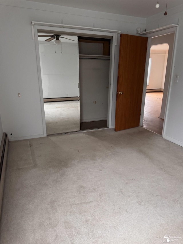 unfurnished bedroom featuring arched walkways, a baseboard radiator, a closet, light carpet, and ceiling fan