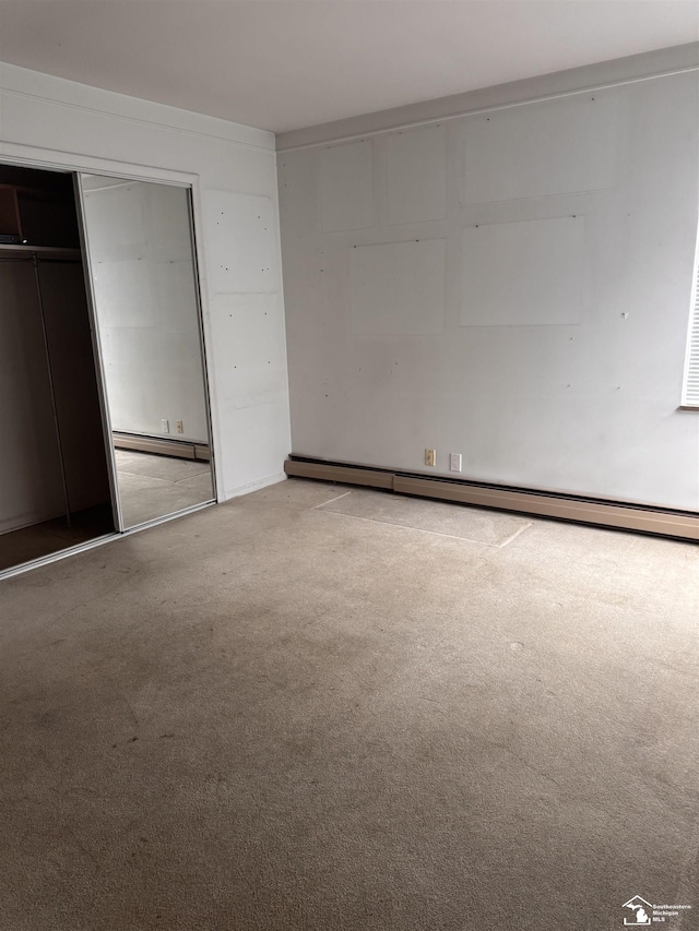 unfurnished bedroom with a baseboard heating unit, carpet, and a closet