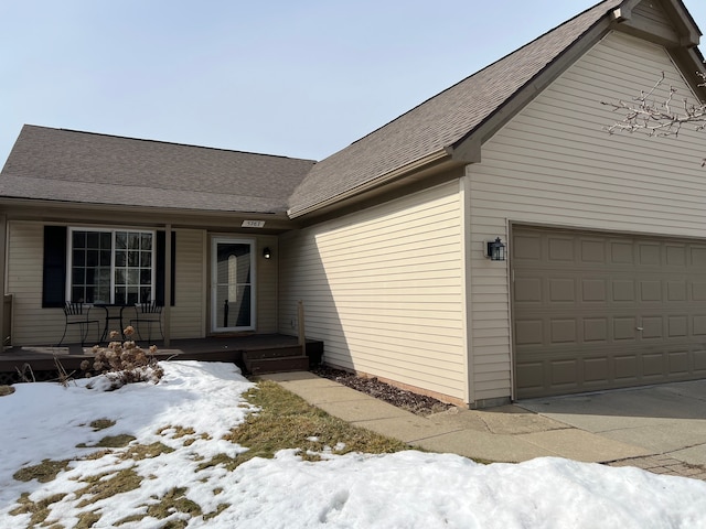 view of front of home featuring a garage and a shingled roof