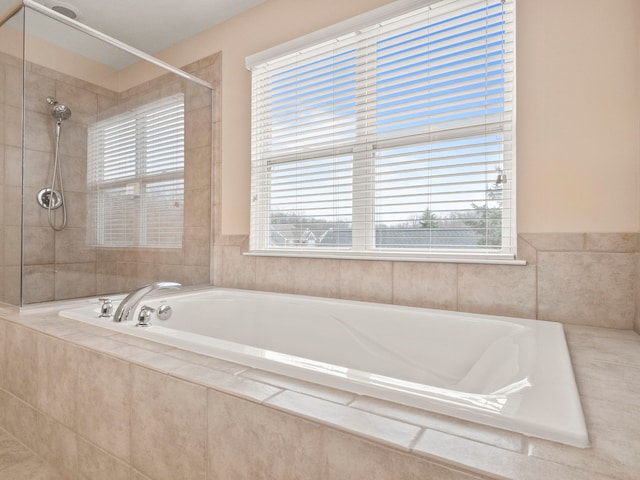 bathroom featuring a wealth of natural light, a bath, and a tile shower