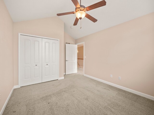 unfurnished bedroom featuring ceiling fan, baseboards, lofted ceiling, carpet flooring, and a closet