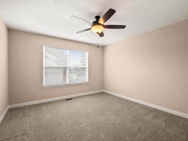 carpeted spare room featuring visible vents, ceiling fan, and baseboards