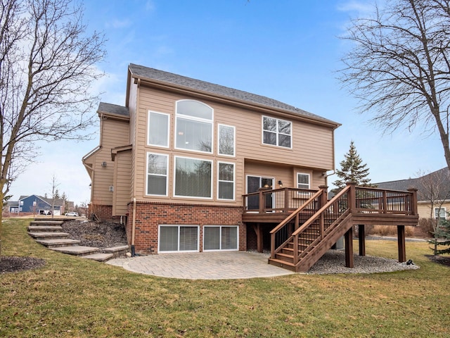 rear view of property featuring a lawn, a deck, a patio, brick siding, and stairs