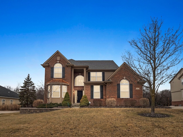 traditional-style house featuring brick siding, a shingled roof, and a front yard