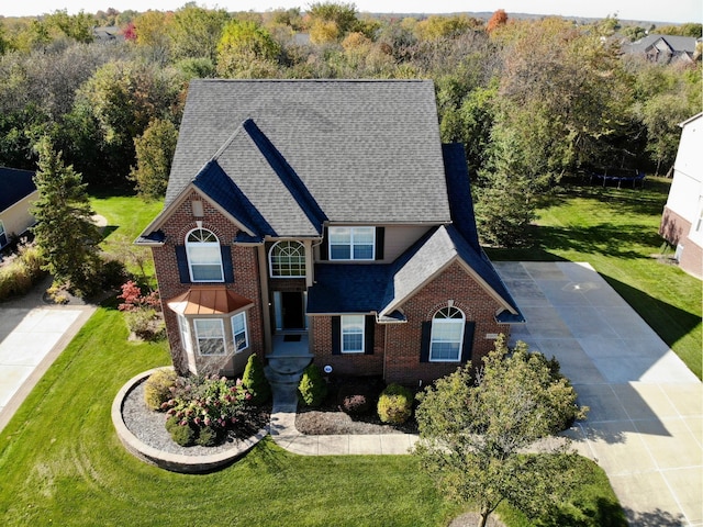 view of front of house with brick siding, a shingled roof, and a front lawn