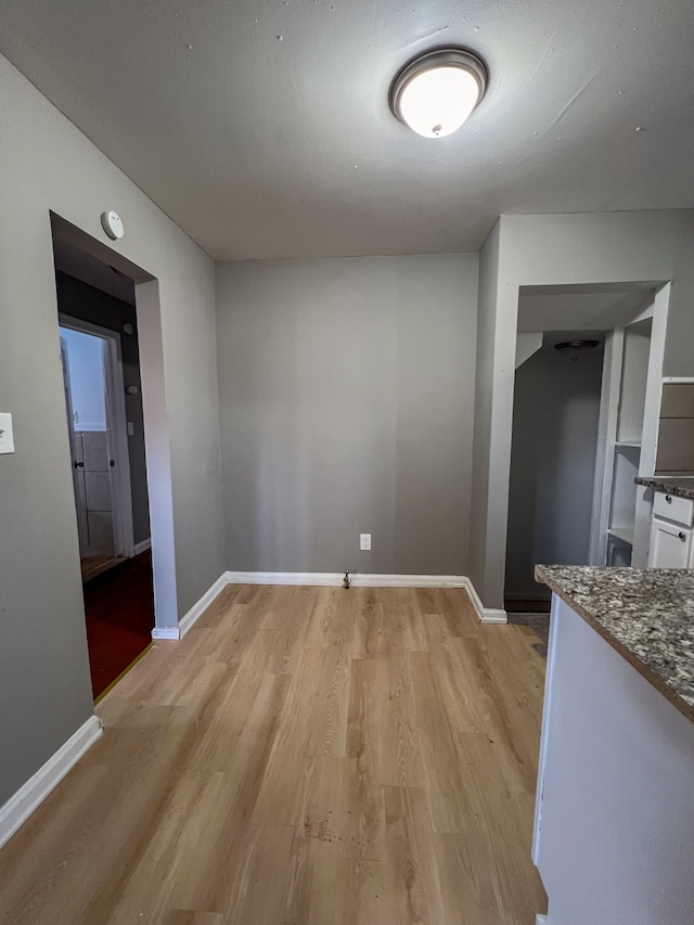 unfurnished dining area with baseboards and light wood finished floors