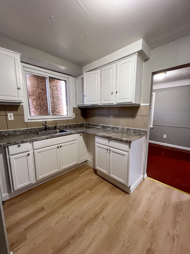 kitchen featuring white cabinetry, a sink, and light wood-style flooring