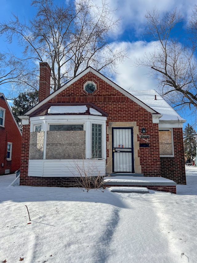 view of front of home featuring brick siding and a chimney