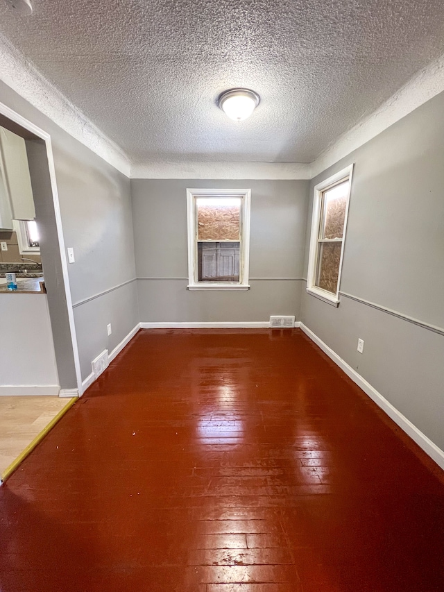 unfurnished room with baseboards, visible vents, and hardwood / wood-style floors