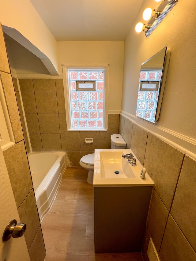 full bathroom featuring a wainscoted wall, tile walls, toilet, vanity, and wood finished floors