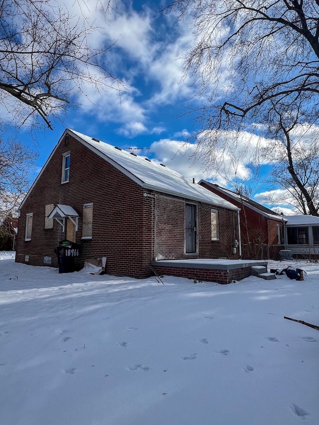 view of snow covered exterior with brick siding