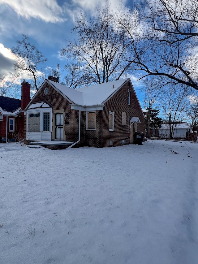 view of front facade featuring a chimney and brick siding