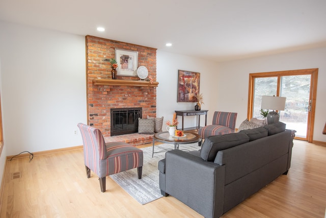 living room with light wood finished floors, a fireplace, and baseboards