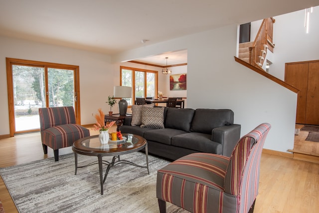 living area featuring stairs, baseboards, light wood finished floors, and an inviting chandelier