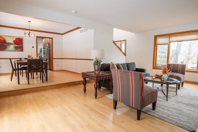 living room featuring a chandelier, visible vents, light wood-style flooring, and baseboards