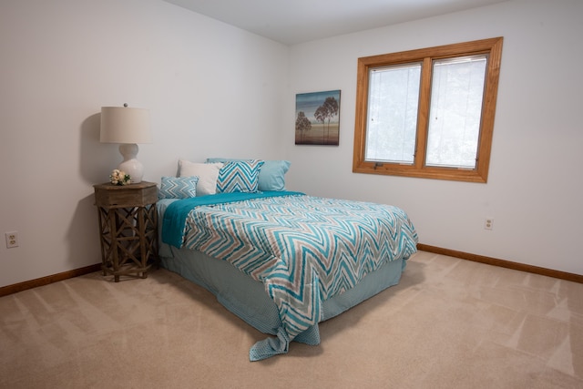 bedroom with baseboards and light colored carpet